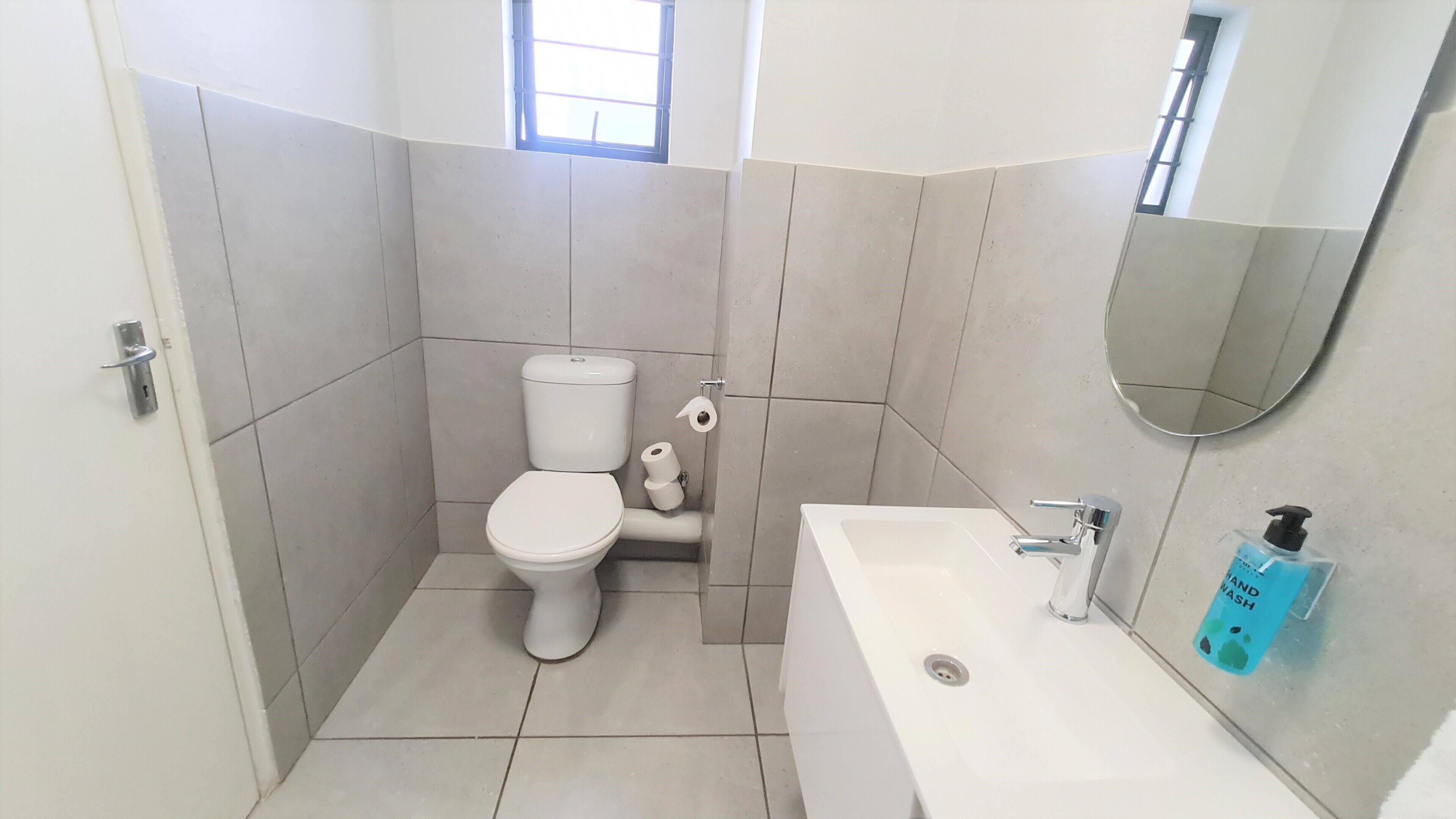 A small, clean bathroom with a toilet, sink, and mirror.
