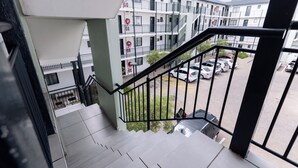 A staircase leading to a balcony overlooking a parking area with multiple cars and a building with balconies. - MINT Express Sandton View (Sandton)