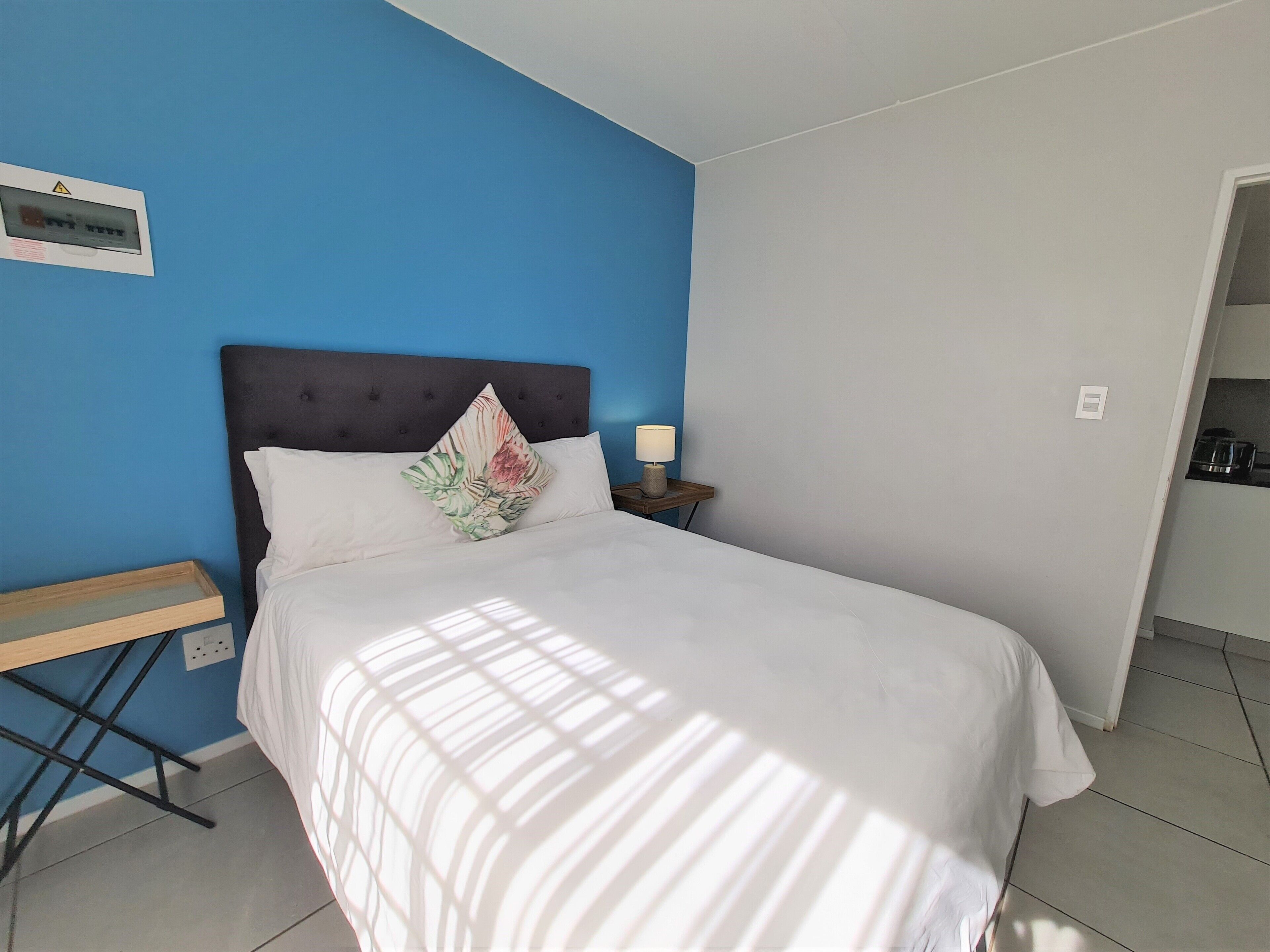 Un dormitorio con una cama, una mesita de noche, una lámpara y un enchufe.