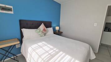 Une chambre à coucher avec un lit, une table de chevet, une lampe et une prise de courant.