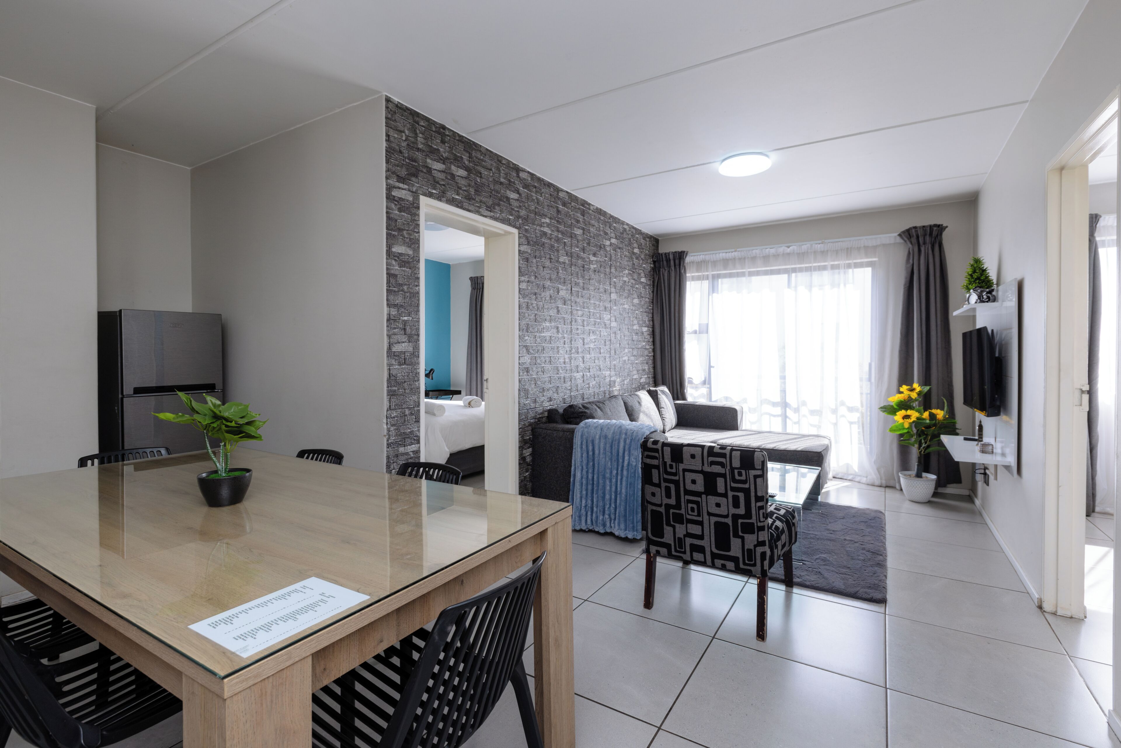 Una habitación de hotel moderna con comedor, sala de estar y televisión.