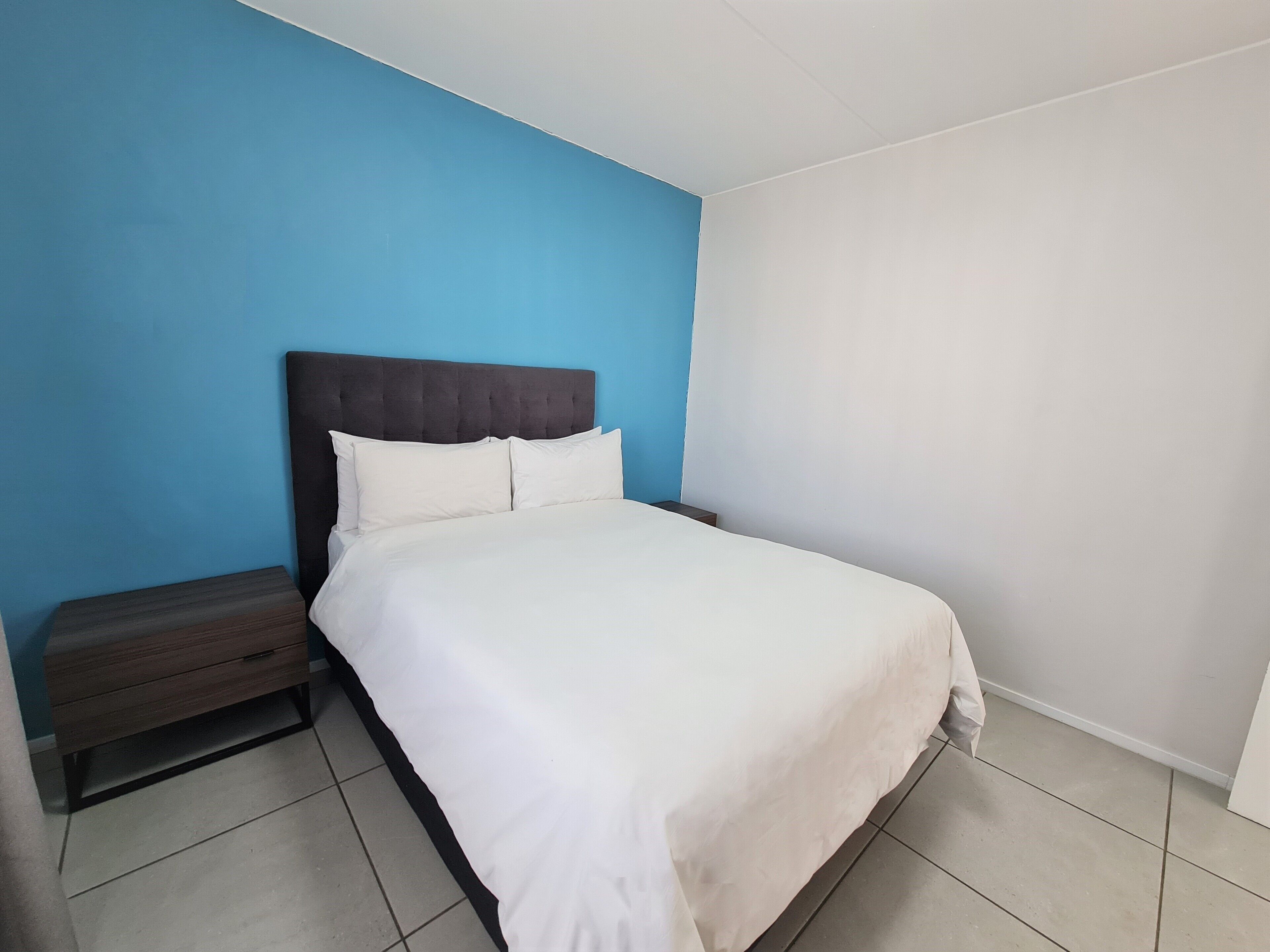 Ein Schlafzimmer mit einem Bett, einem Nachttisch und einer blauen Wand.