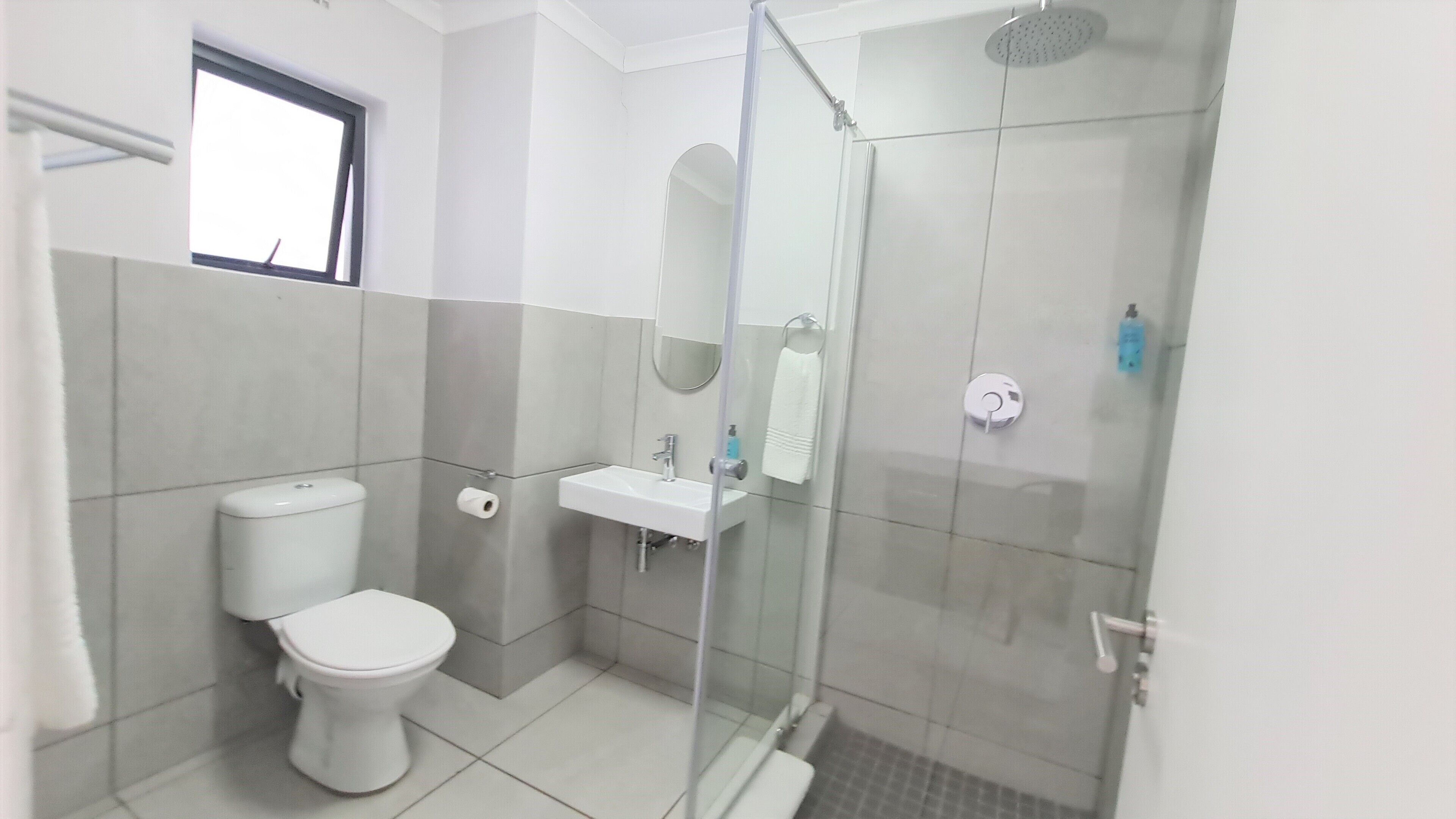 Un baño con inodoro, lavamanos y ducha con mampara de vidrio.