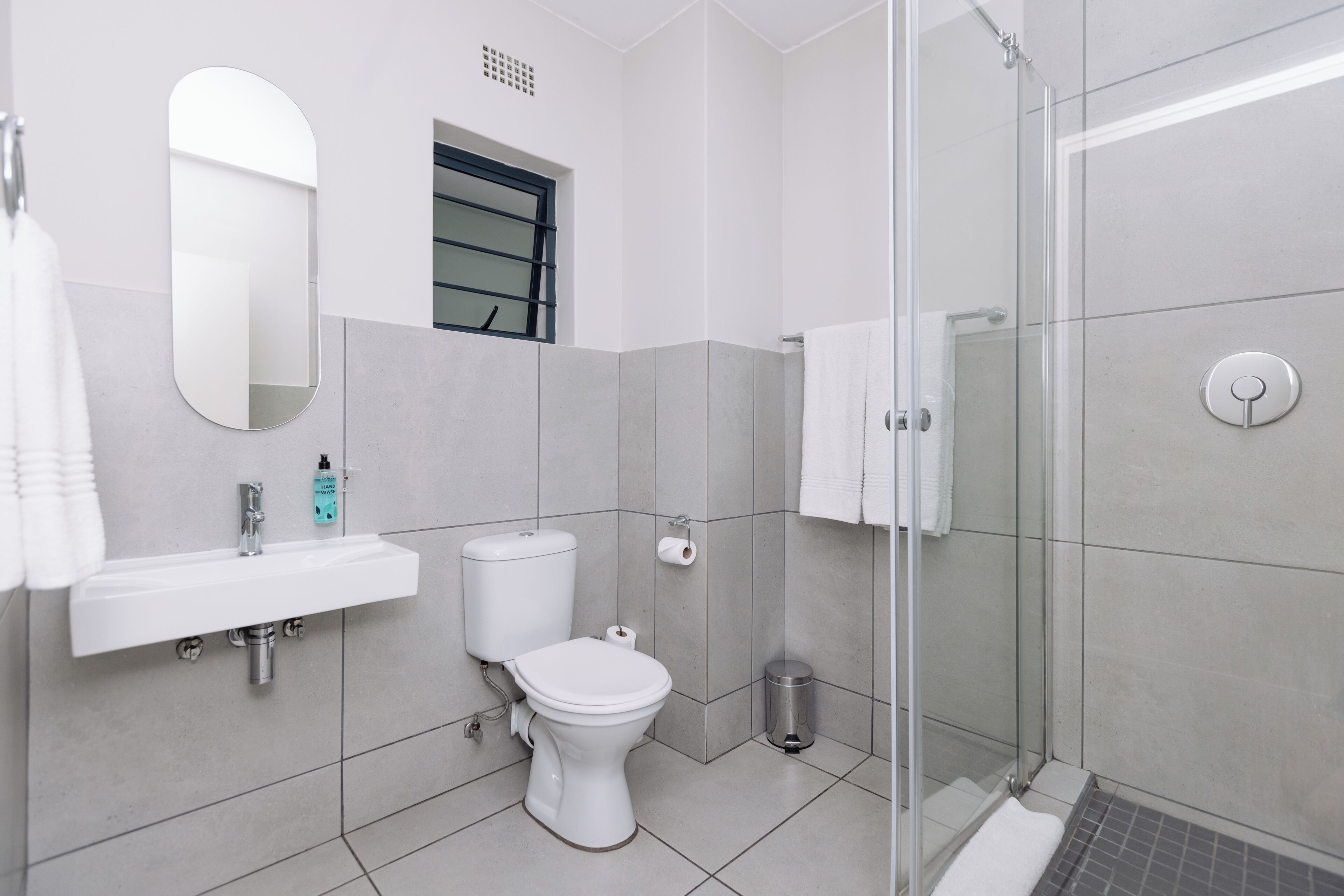 A modern bathroom with a sink, toilet, and glass shower enclosure.