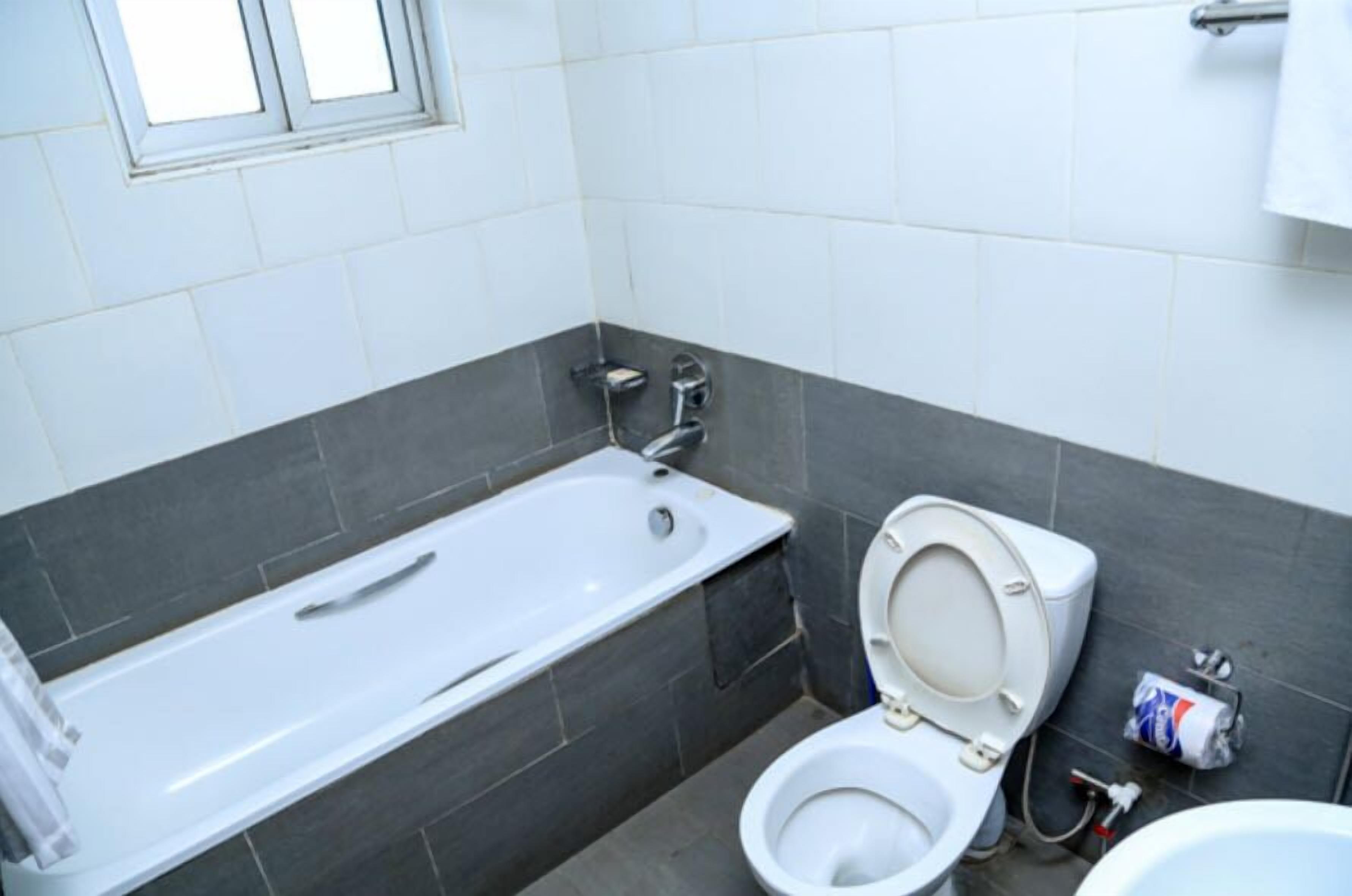 Un baño con bañera, inodoro y ventana.