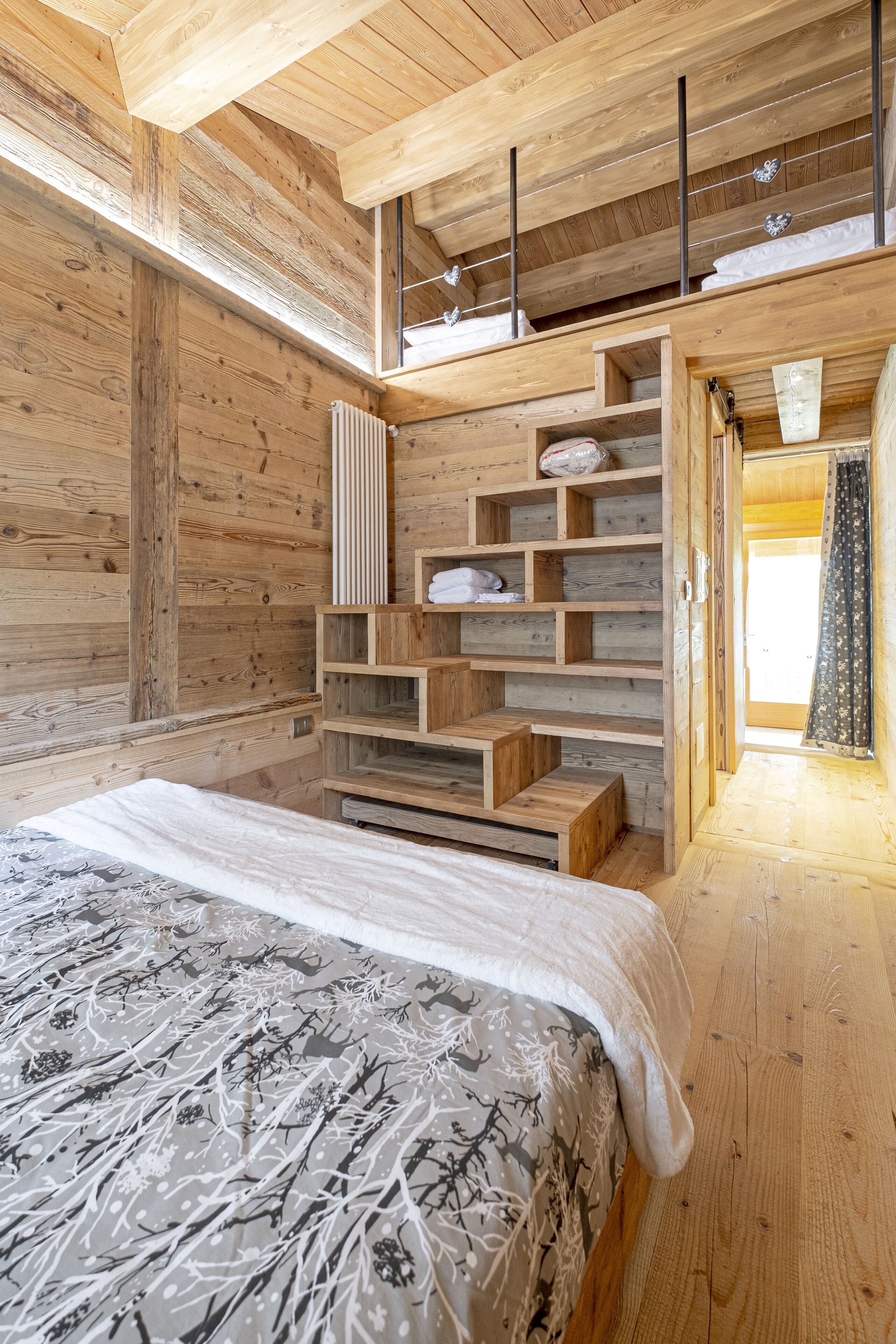 A wooden cabin bedroom with a bed, built-in shelves, and a radiator.