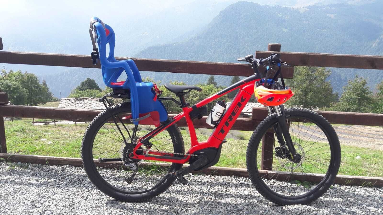 Een rode mountainbike met een waterfles en een blauwe opvouwbare stoel in een bergachtig gebied.
