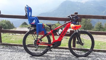Een rode mountainbike met een waterfles en een blauwe opvouwbare stoel in een bergachtig gebied.