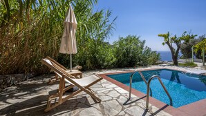 Ein Poolbereich mit Liegestühlen und Blick auf den Ozean.