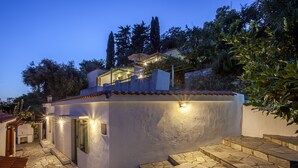 Eine moderne Villa mit einer Steinterrasse, einem kleinen Pool und einer überdachten Sitzgelegenheit im Freien.