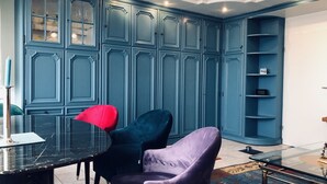 A room with a dark blue cabinet, a glass table, and two chairs.