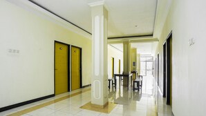 Corredor com portas amarelas, um pilar central e um banco.