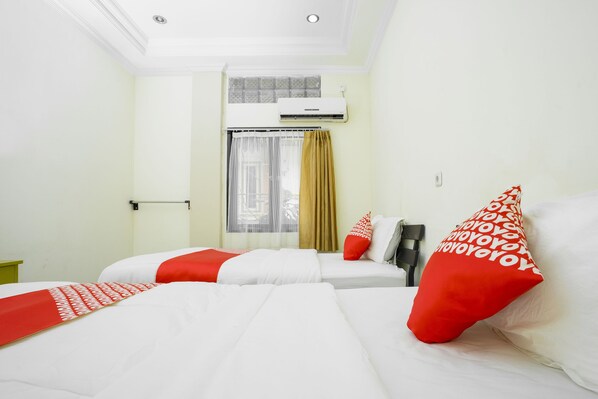 A hotel room with two beds, a window with curtains, an air conditioning unit, and a green nightstand. - OYO 2319 Tengkawang Residence (Samarinda)