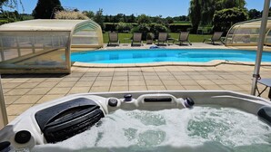 Hidromasaje con vista despejada a la piscina y sillones de descanso al fondo.