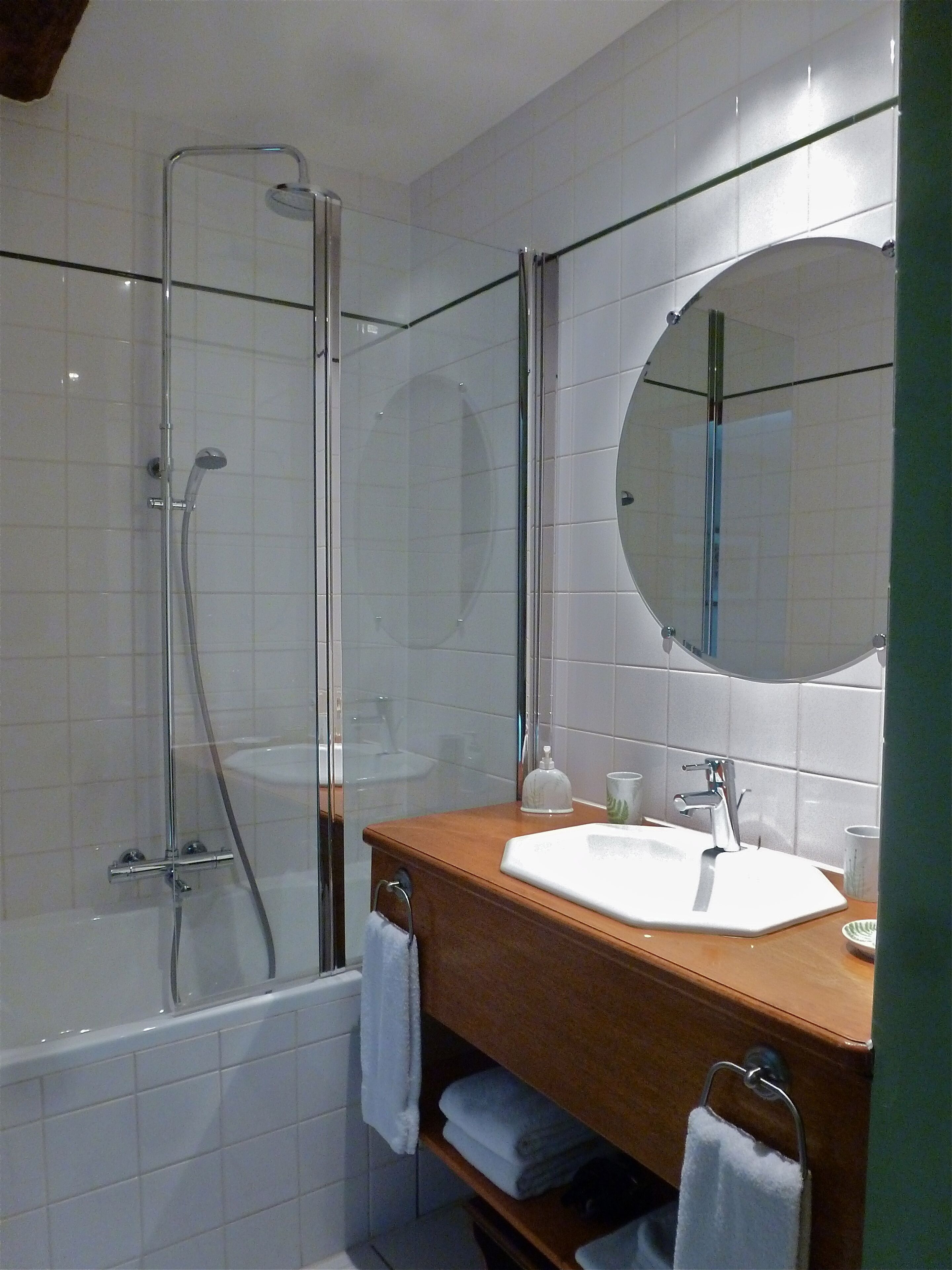 Une salle de bain avec une douche à parois de verre, un lavabo blanc et un miroir au-dessus du lavabo.