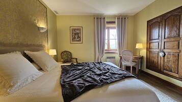 A hotel room with a large bed, a desk, a chair, and a wardrobe.