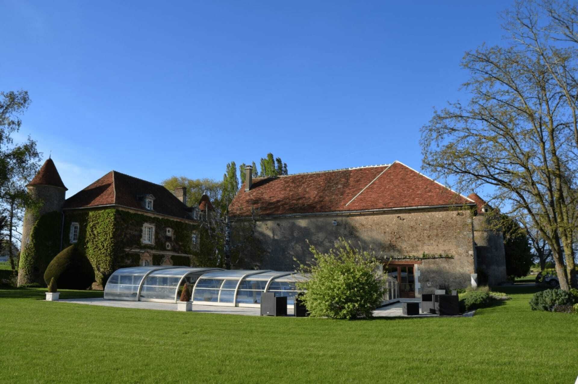 A historic building with a red-tiled roof, a tower, and a conservatory.