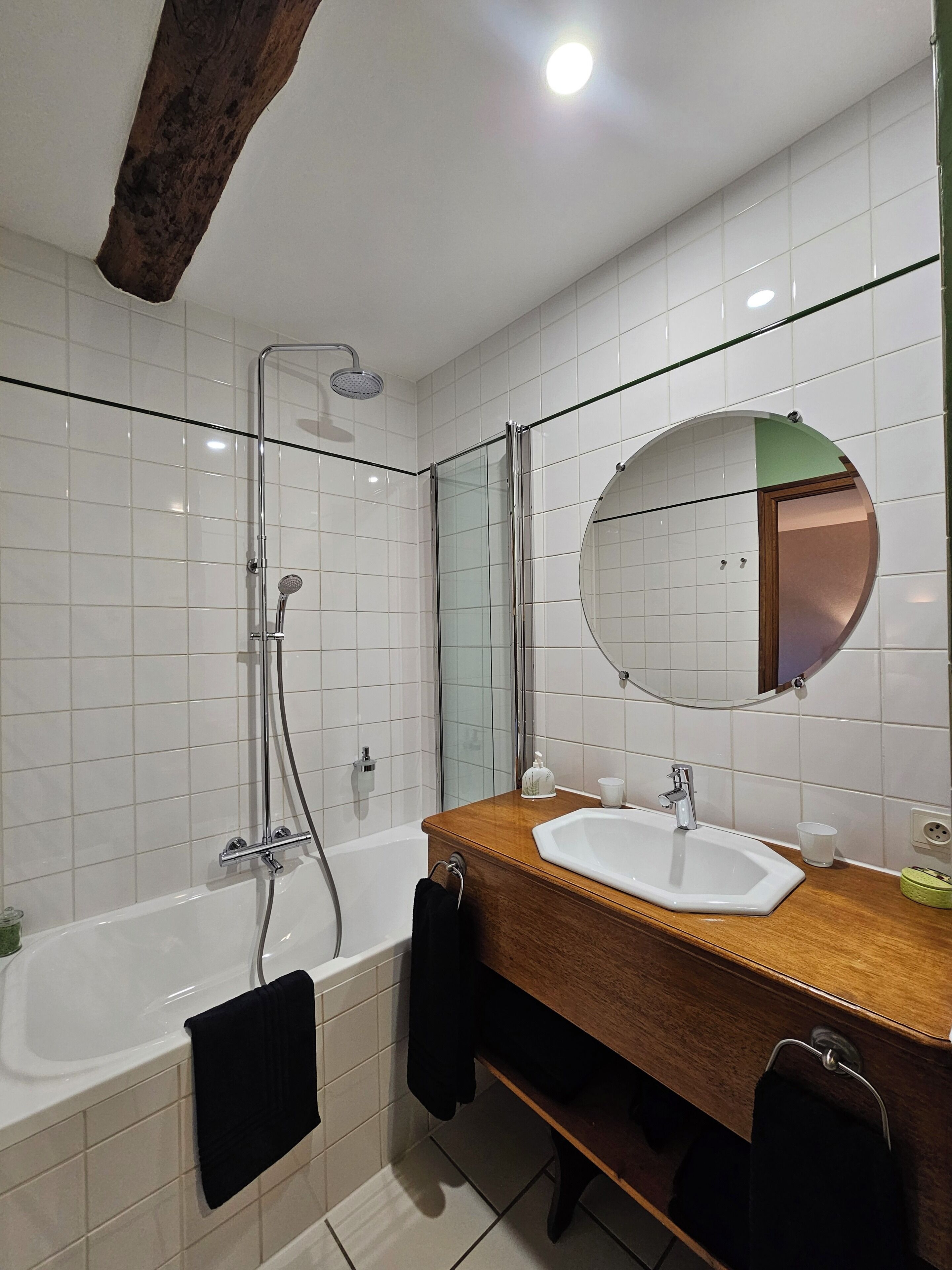 A bathroom with a bathtub, a sink, a mirror, and a shower.