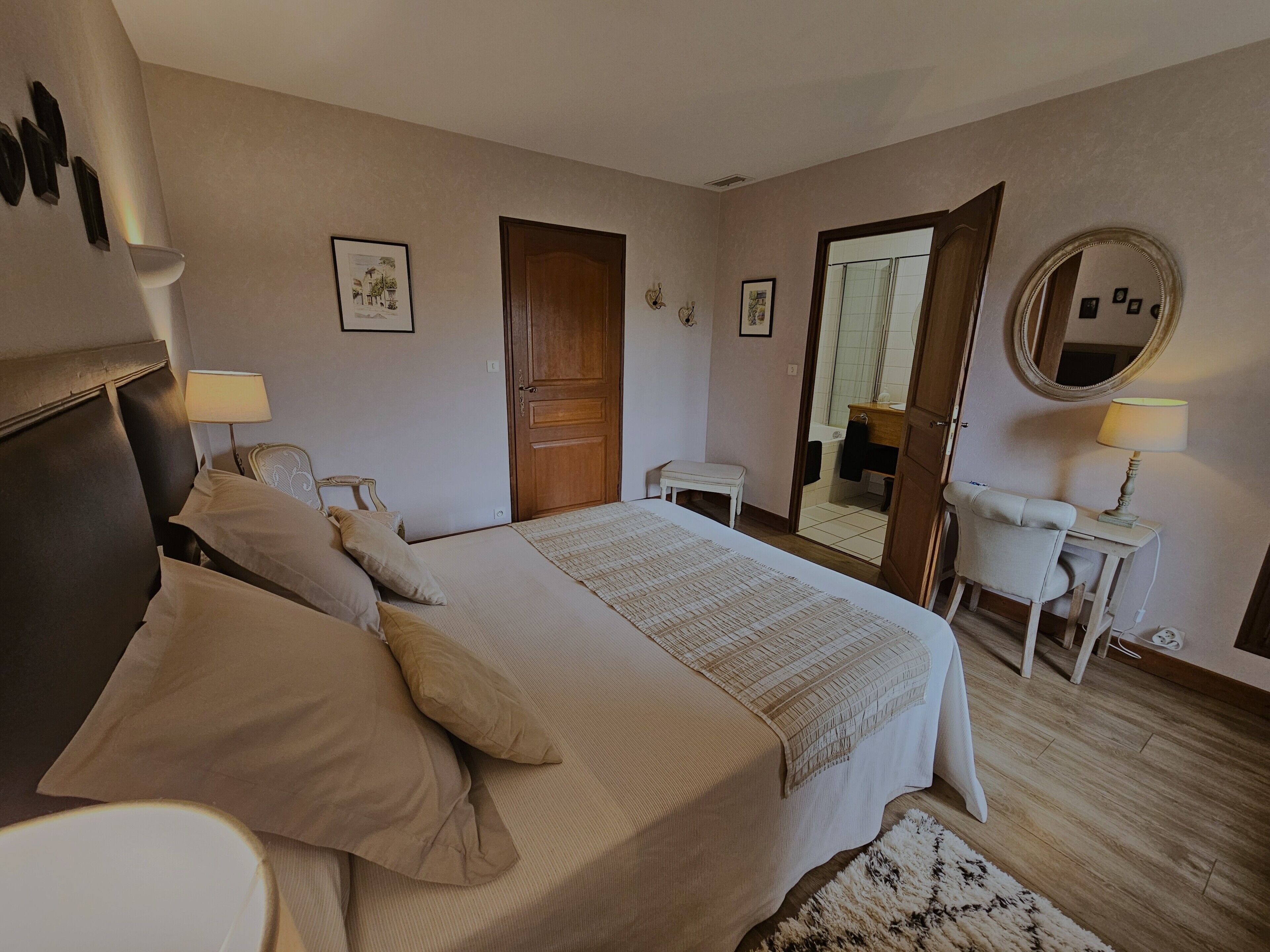 Quarto com cama, mesas de cabeceira, espelho e porta.