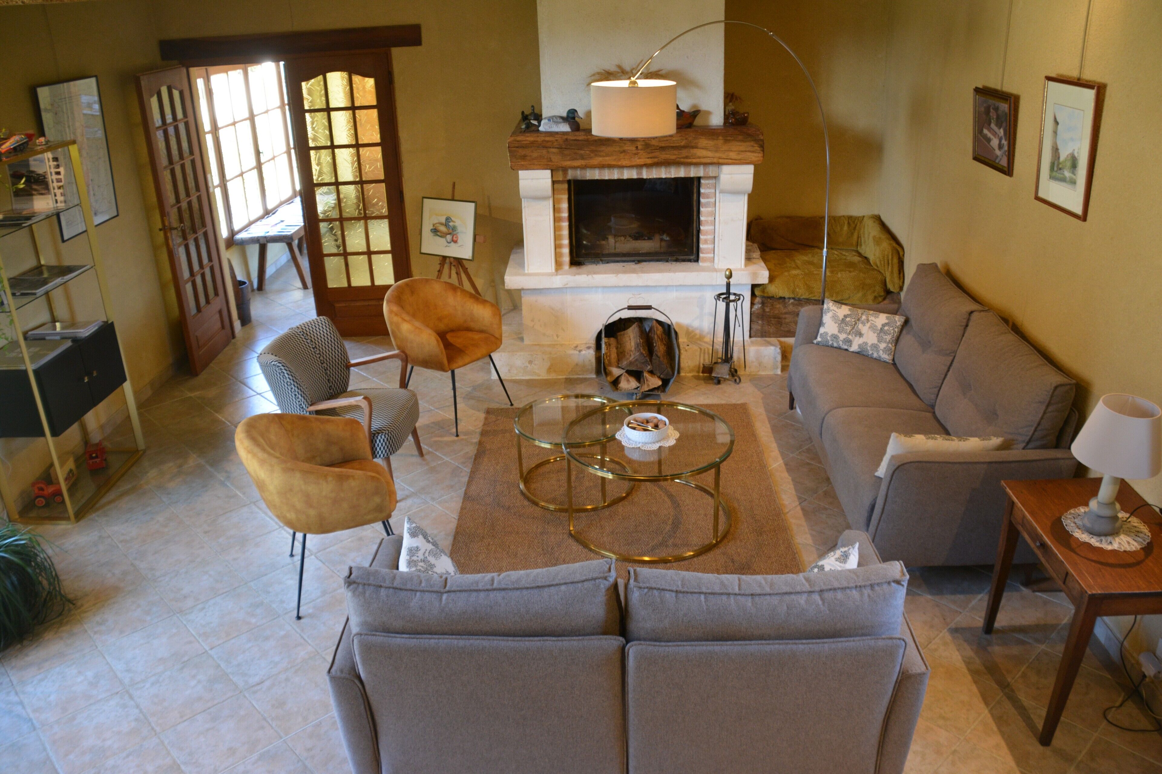 A living room with a fireplace, sofa, armchair, coffee table, and a side table with a lamp.