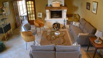 A living room with a fireplace, sofa, armchair, coffee table, and a side table with a lamp.