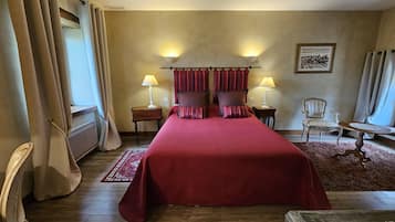 A hotel room with a large bed, two bedside tables with lamps, a chair, a small table, and a rug.