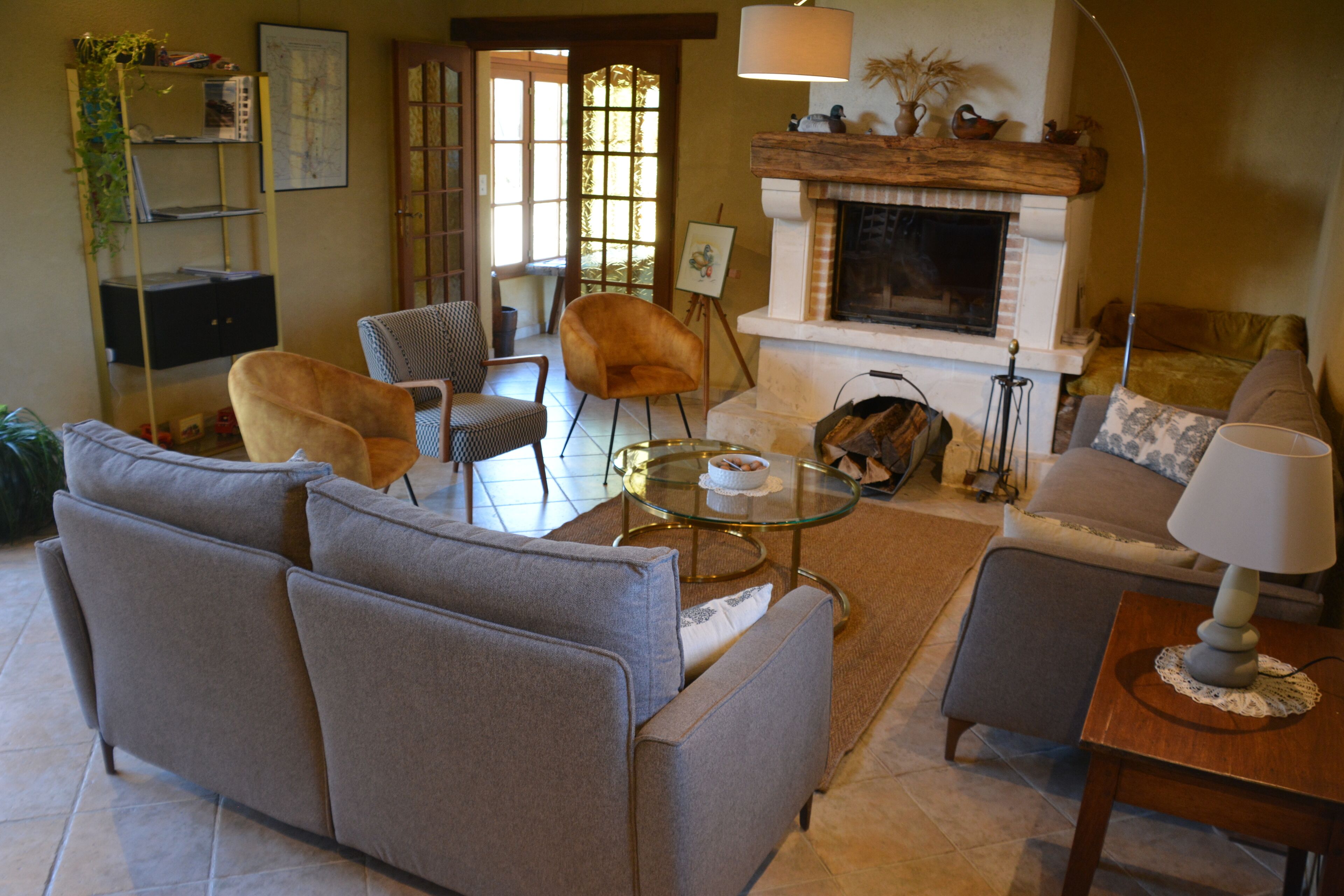 A living room with a fireplace, sofas, armchairs, a coffee table, and a bookshelf.
