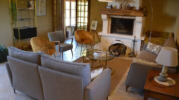 A living room with a fireplace, sofas, armchairs, a coffee table, and a bookshelf.