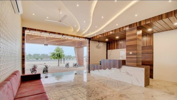 Una zona de recepción moderna con suelo de mármol, un sofá rojo y un mostrador de madera.