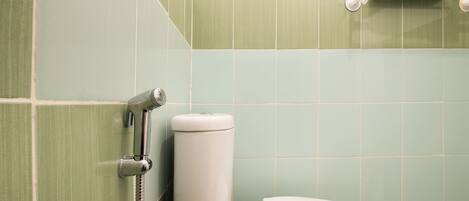 A bathroom with green tiles, a toilet, and a towel rack.
