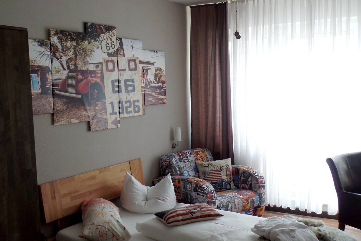 Un dormitorio con cama, sofá y una pared decorada con señales de carretera antiguas.