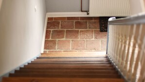 A wooden staircase with a brick wall at the bottom. - Idyllic holiday home on a listed farm (Natendorf)