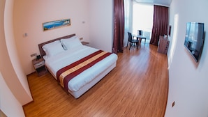 Ein Hotelzimmer mit Bett, Schreibtisch, Stuhl, Fernseher und einem Gemälde an der Wand.