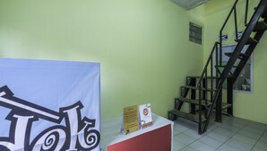 A staircase with a handrail and a sign on a counter. - Hotel O Pondok Nabil (Cileunyi)