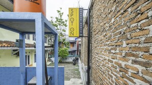 A narrow alley with a brick wall on one side and a building with a blue facade on the other. A yellow sign with the text "SPOTON" and "PONDOK NABIL" is visible. - Hotel O Pondok Nabil (Cileunyi)