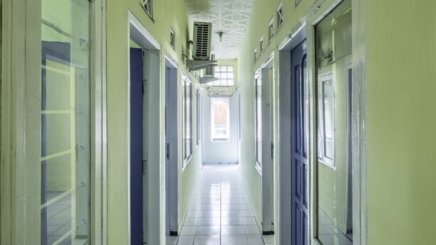 A long, narrow hallway with doors on both sides, leading to a bright room at the end. - Hotel O Pondok Nabil (Cileunyi)