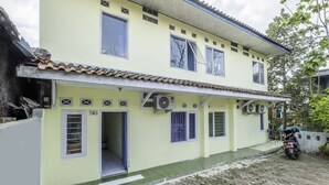 A two-story building with a tiled roof, multiple windows, and a motorcycle parked outside. - Hotel O Pondok Nabil (Cileunyi)