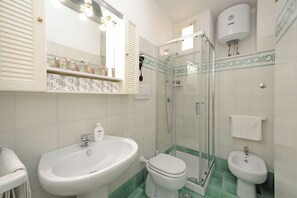 Ein Badezimmer mit Waschbecken, Toilette, Bidet und Duschkabine.