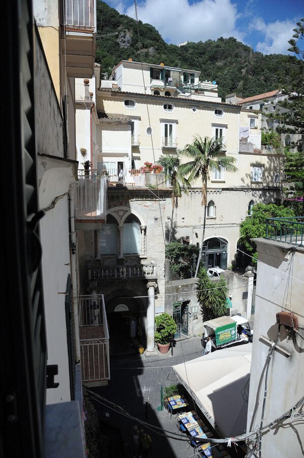 A narrow street with buildings, a palm tree, and a white truck.