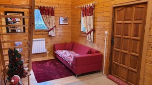 A cozy room with a red sofa, a small Christmas tree, and wooden walls.