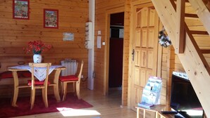 A wooden cabin interior with a dining area, a fireplace, and a small table with magazines.
