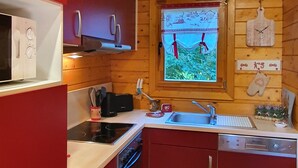 A compact kitchen with wooden walls, a window with a view, and modern appliances.