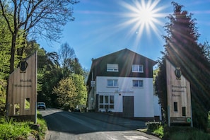 A two-story building with a sign indicating it is a hotel. There is a car parked in front, and the sun is shining brightly. - Double room - Landgasthof Elsebach (Vöhl)