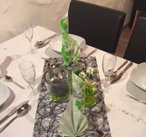 A dining table set with plates, cutlery, glasses, and decorative elements including a glass pitcher and floral arrangements. - Double room - Landgasthof Elsebach (Vöhl)