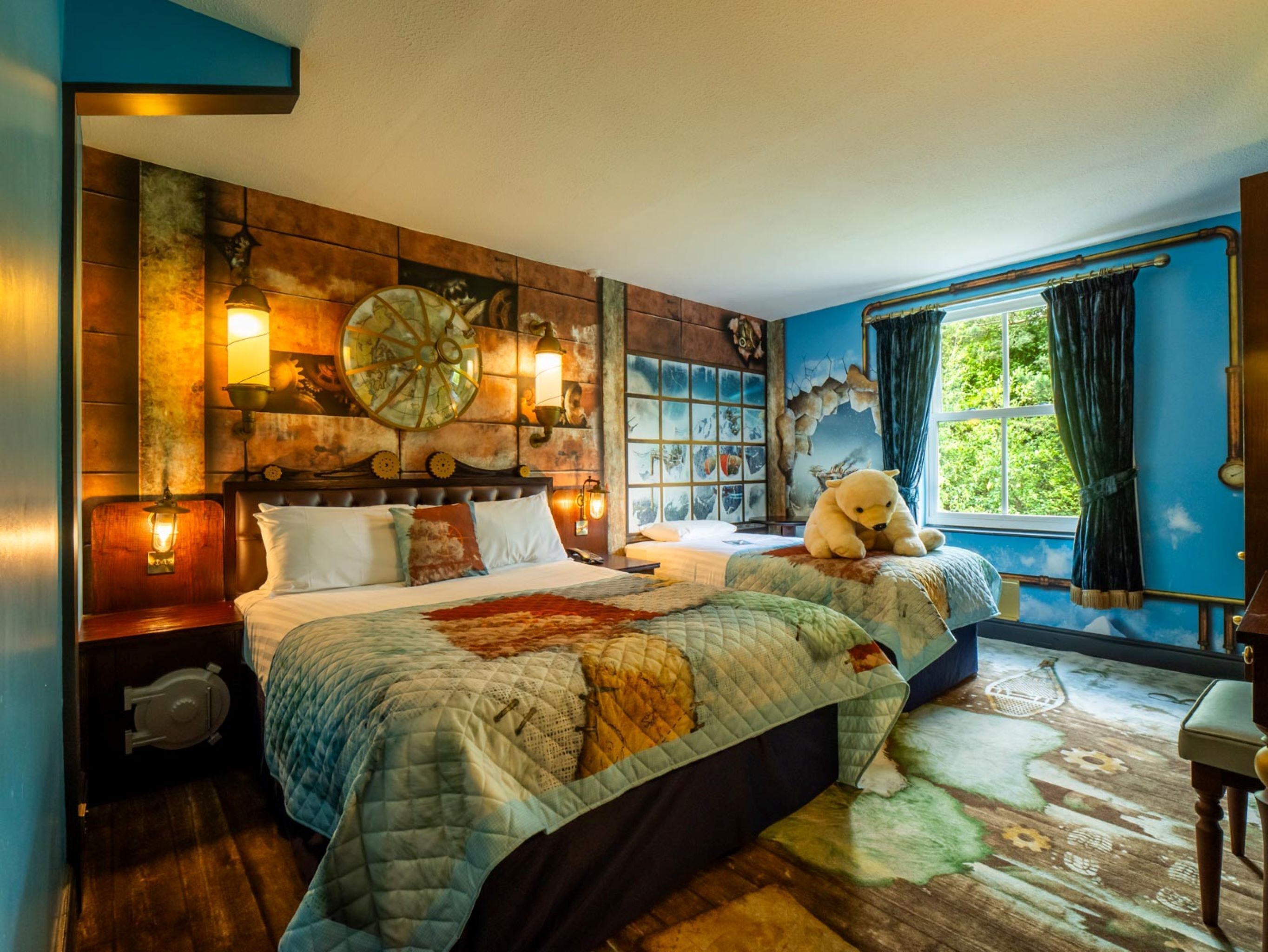Una habitación con una cama grande, una cama más pequeña, un reloj de pared, una ventana con cortinas y un osito de peluche sobre la cama más pequeña.