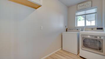 A laundry room with a washing machine, dryer, and a sign above the window.