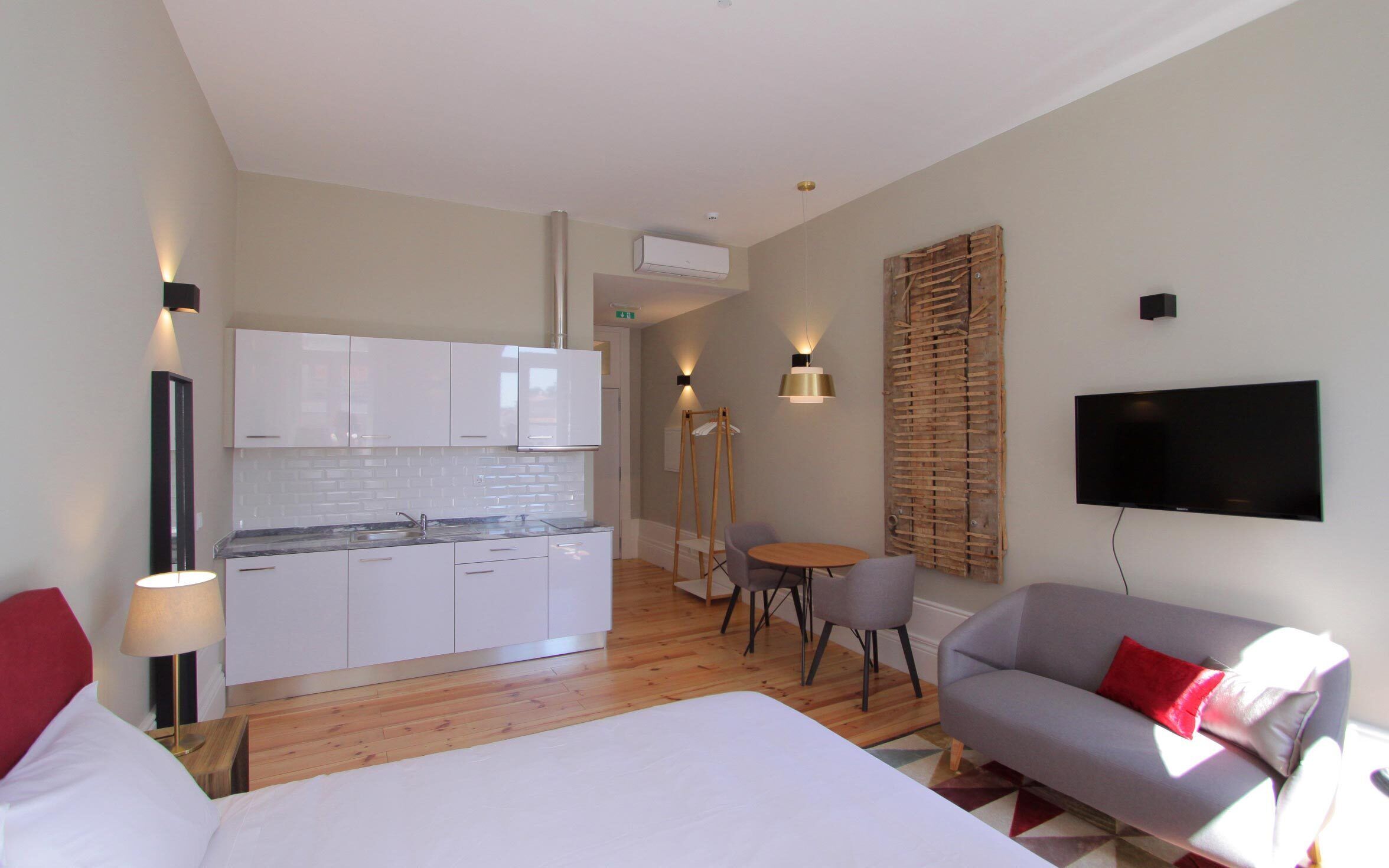 Una habitación de hotel moderna con una cama grande, un sofá, una mesa de comedor y una kitchenette.