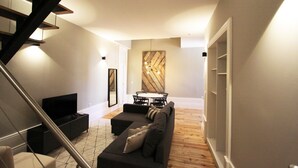 A modern living room with a sofa, TV, and dining area. - Duque de Loulé (Porto)