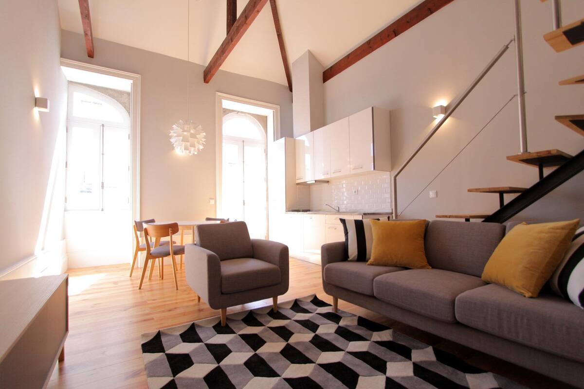 A modern living room with a sofa, armchair, and dining area.