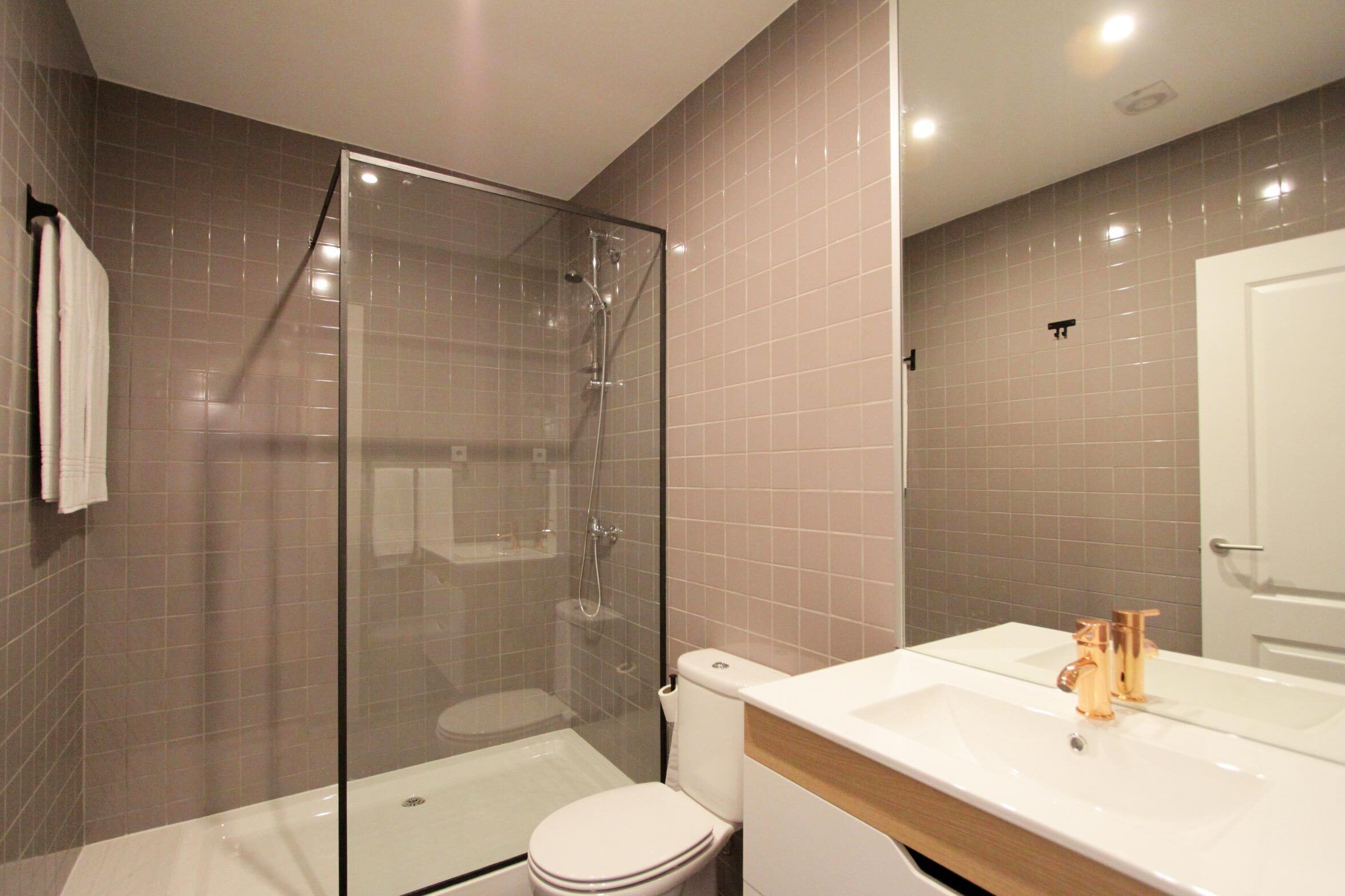 Un bagno moderno con doccia vetrata, un water bianco e un lavabo con piano in legno.